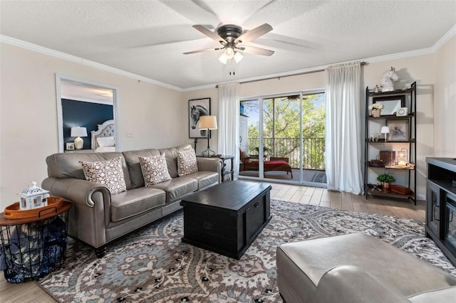 living room with ceiling fan, crown molding, light hardwood / wood-style flooring, and a textured ceiling