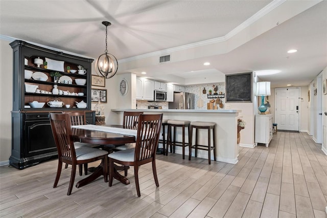 dining area featuring ornamental molding, a chandelier, and light hardwood / wood-style floors