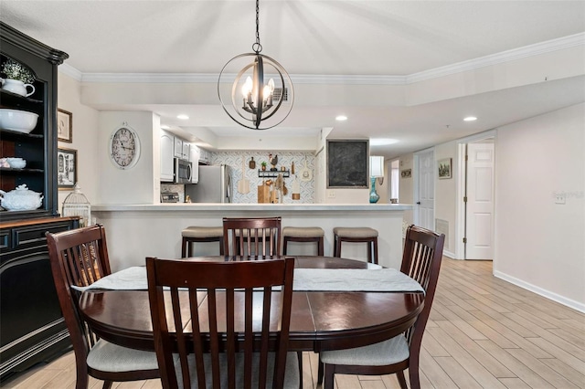 dining room with crown molding, an inviting chandelier, and light hardwood / wood-style floors