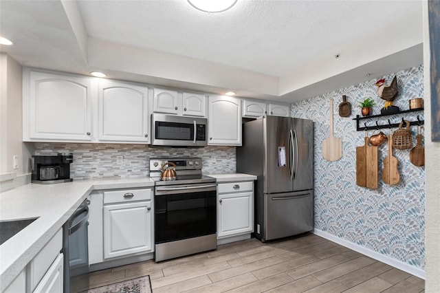 kitchen featuring tasteful backsplash, stainless steel appliances, a textured ceiling, and white cabinets