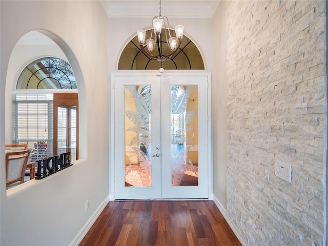 entryway with an inviting chandelier, crown molding, dark hardwood / wood-style floors, and french doors