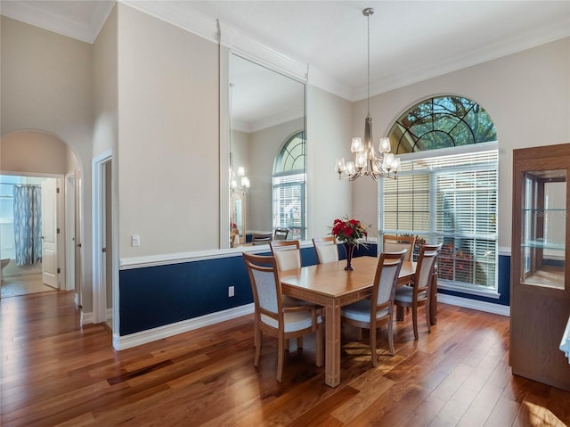 dining room with a notable chandelier, dark wood-type flooring, ornamental molding, and a high ceiling