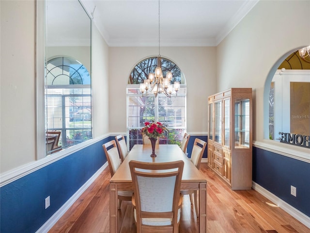 dining space with hardwood / wood-style flooring, ornamental molding, and an inviting chandelier