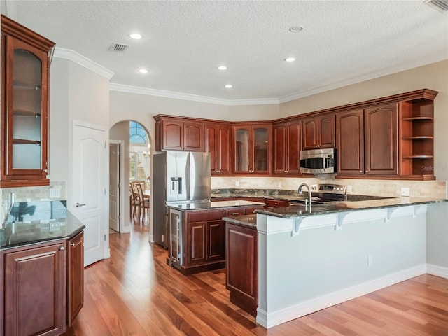 kitchen featuring dark wood-type flooring, stainless steel appliances, tasteful backsplash, and dark stone countertops