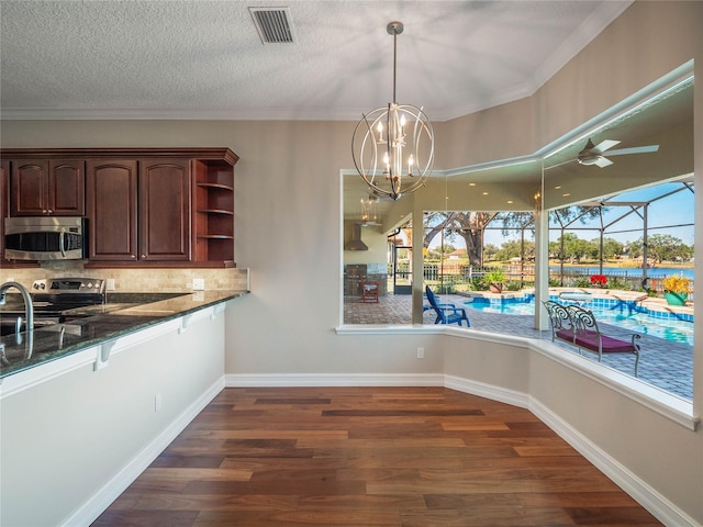 kitchen with dark hardwood / wood-style flooring, decorative backsplash, hanging light fixtures, dark stone counters, and stainless steel appliances