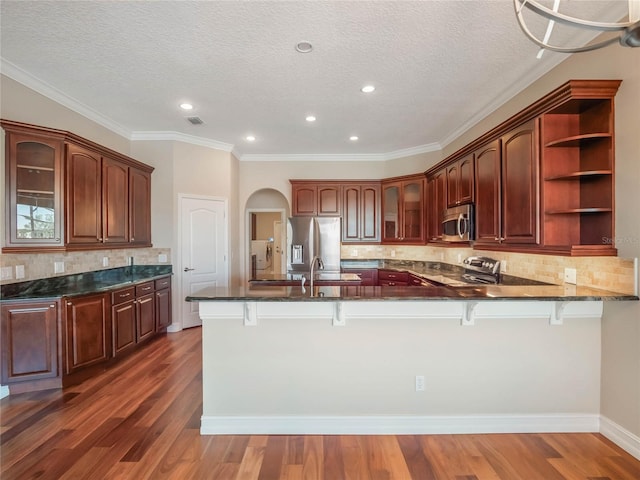 kitchen featuring appliances with stainless steel finishes, dark hardwood / wood-style flooring, kitchen peninsula, and a breakfast bar area