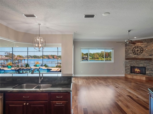 kitchen featuring pendant lighting, sink, a fireplace, wood-type flooring, and ceiling fan with notable chandelier