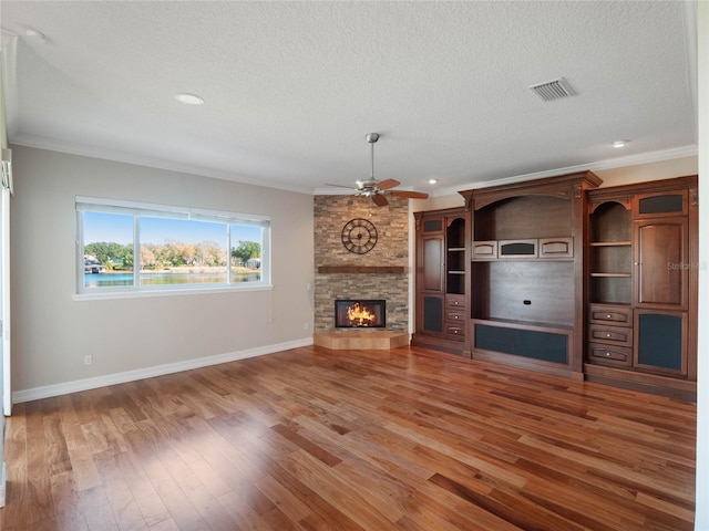 unfurnished living room featuring ornamental molding, hardwood / wood-style floors, a textured ceiling, and a fireplace