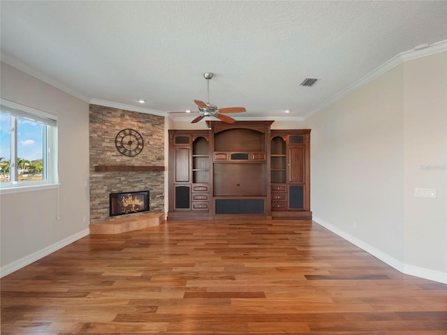 unfurnished living room featuring hardwood / wood-style floors, a large fireplace, ceiling fan, crown molding, and a textured ceiling