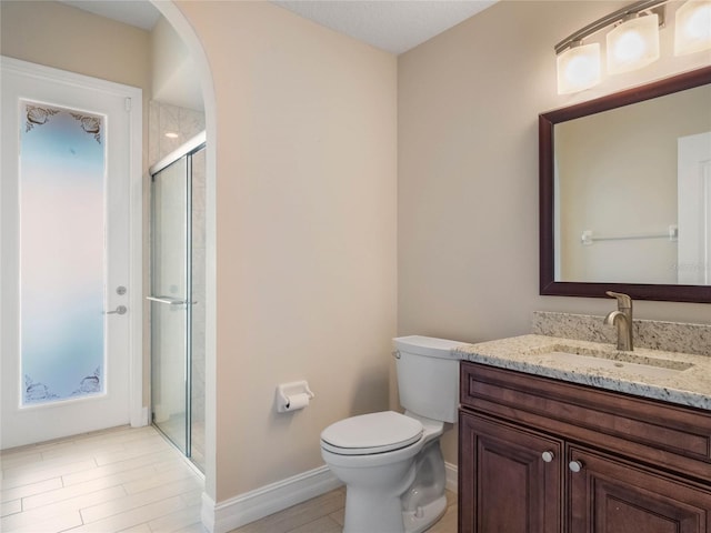 bathroom with vanity, toilet, and a shower with door