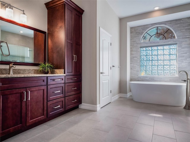 bathroom featuring a washtub, vanity, tile patterned flooring, and a healthy amount of sunlight