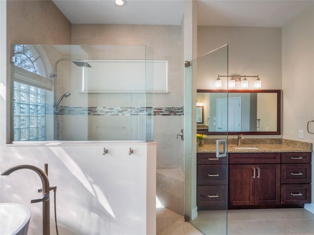 bathroom featuring tile patterned flooring, vanity, and a tile shower