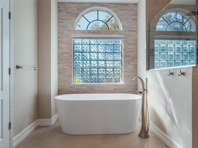 bathroom with tile patterned flooring and a tub to relax in