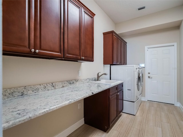 clothes washing area with cabinets, separate washer and dryer, and sink