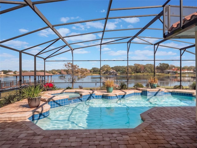 view of swimming pool featuring a patio, a water view, glass enclosure, pool water feature, and an in ground hot tub