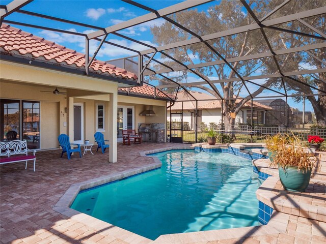 view of pool featuring an in ground hot tub, a patio, ceiling fan, and glass enclosure