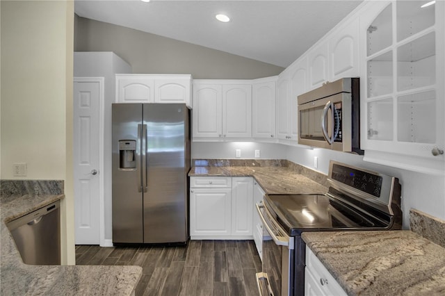 kitchen featuring white cabinetry, appliances with stainless steel finishes, lofted ceiling, and light stone counters