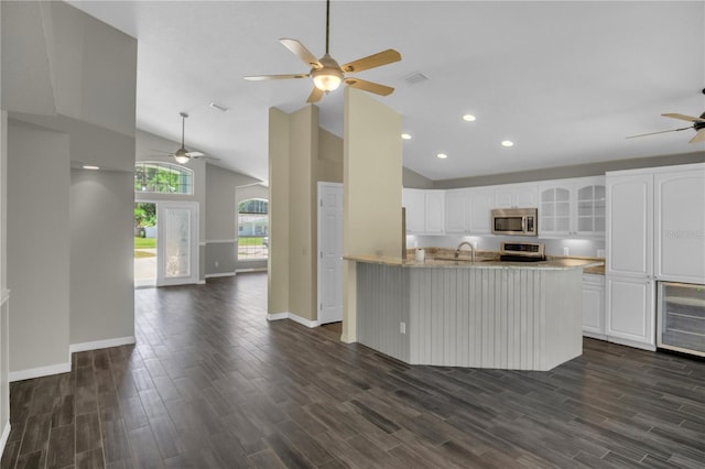 kitchen with dark wood-type flooring, ceiling fan, white cabinetry, stainless steel appliances, and kitchen peninsula