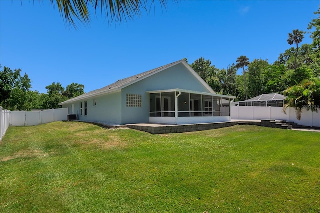 back of house featuring central AC unit, a yard, and a sunroom