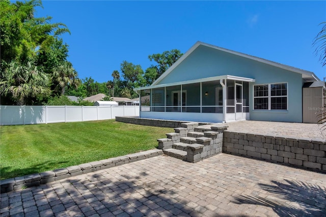 rear view of property featuring a sunroom, a yard, and a patio area