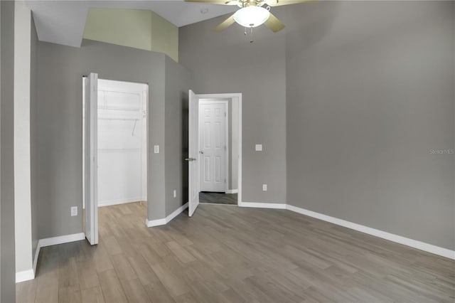 unfurnished bedroom with ceiling fan, a spacious closet, light wood-type flooring, and a closet