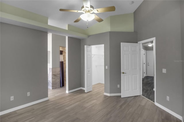 unfurnished bedroom featuring a closet, a walk in closet, ceiling fan, and light hardwood / wood-style flooring