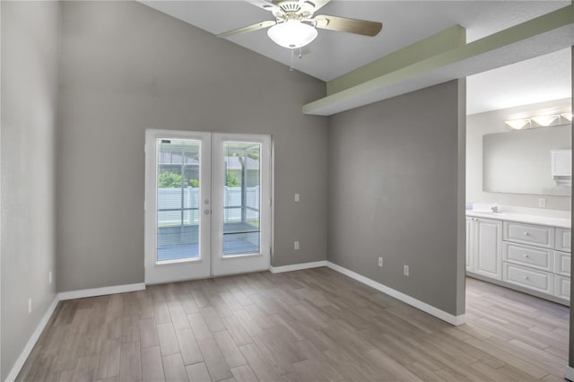 empty room featuring french doors, lofted ceiling, sink, ceiling fan, and light hardwood / wood-style flooring