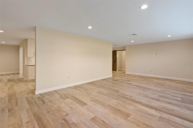 spare room featuring light hardwood / wood-style floors and a textured ceiling