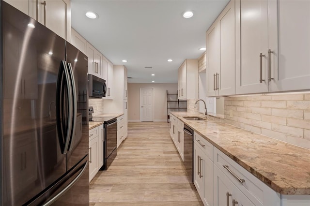 kitchen with light stone counters, white cabinets, sink, and black appliances