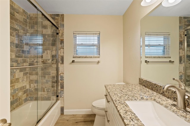 full bathroom featuring toilet, shower / bath combination with glass door, hardwood / wood-style floors, and a wealth of natural light