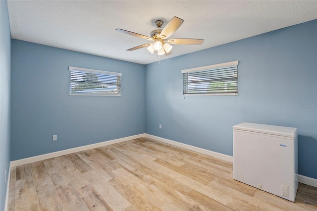 empty room with a textured ceiling, light hardwood / wood-style floors, and ceiling fan