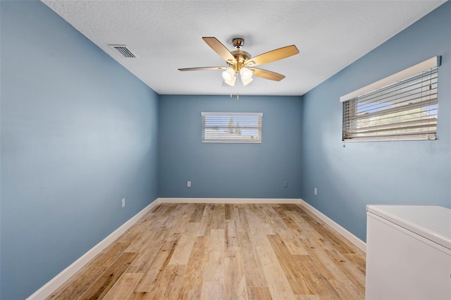 unfurnished room featuring ceiling fan, a healthy amount of sunlight, a textured ceiling, and light hardwood / wood-style floors