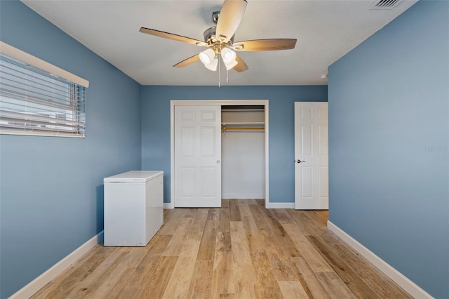 unfurnished bedroom with fridge, ceiling fan, light hardwood / wood-style floors, and a closet