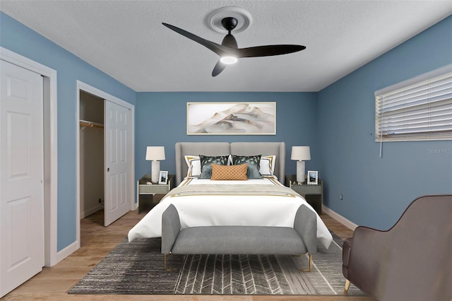 bedroom featuring ceiling fan, light hardwood / wood-style flooring, a closet, and a textured ceiling