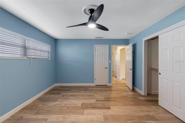 unfurnished bedroom with ceiling fan, a textured ceiling, and light wood-type flooring