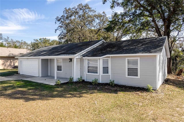 single story home featuring a shingled roof, a front yard, driveway, and an attached garage