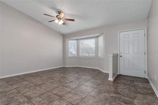 spare room with lofted ceiling, ceiling fan, a textured ceiling, and baseboards