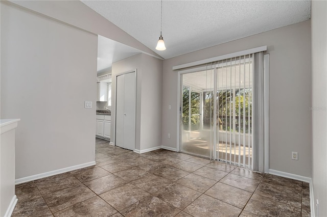 spare room featuring lofted ceiling, tile patterned flooring, a textured ceiling, and baseboards