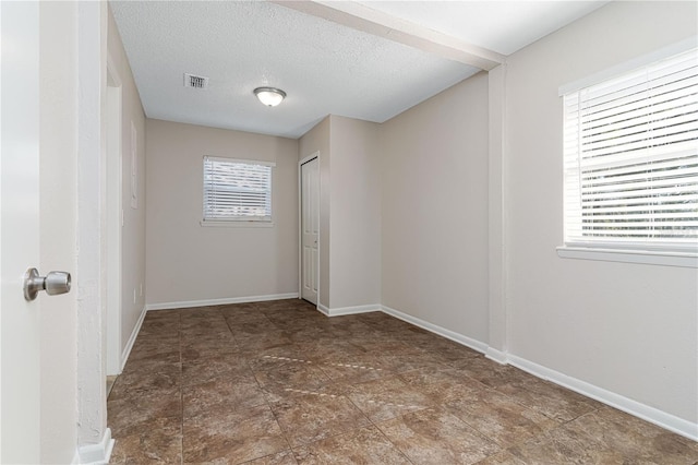 spare room featuring baseboards, visible vents, and a textured ceiling