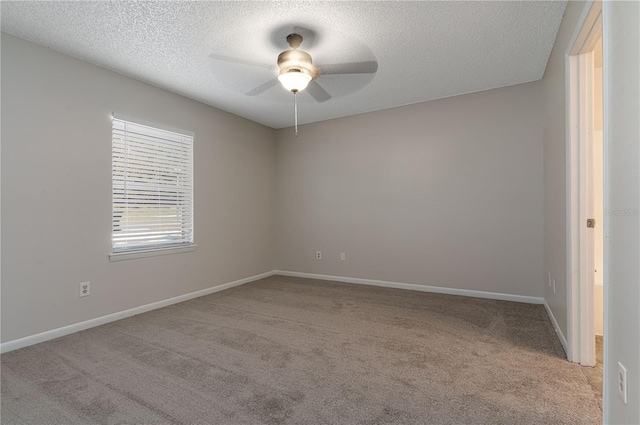 empty room with light carpet, ceiling fan, baseboards, and a textured ceiling