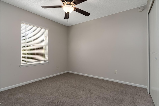 carpeted empty room with a textured ceiling, a ceiling fan, and baseboards