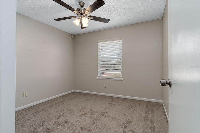 empty room with a textured ceiling, carpet flooring, a ceiling fan, and baseboards