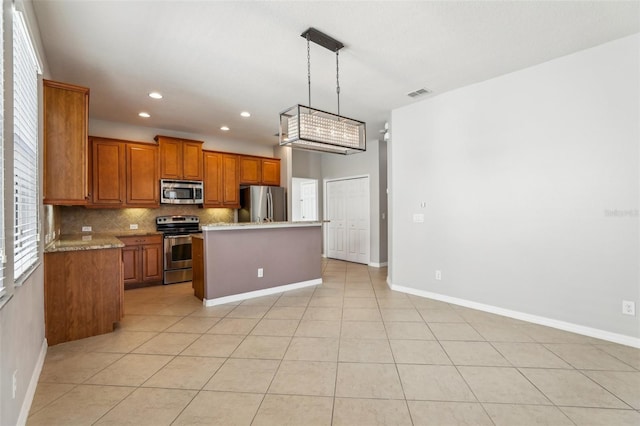 kitchen with appliances with stainless steel finishes, decorative light fixtures, tasteful backsplash, a center island, and light tile patterned floors