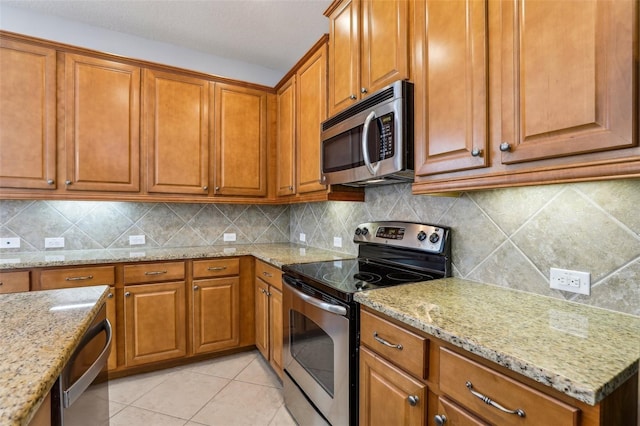 kitchen with light stone counters, light tile patterned floors, tasteful backsplash, and appliances with stainless steel finishes