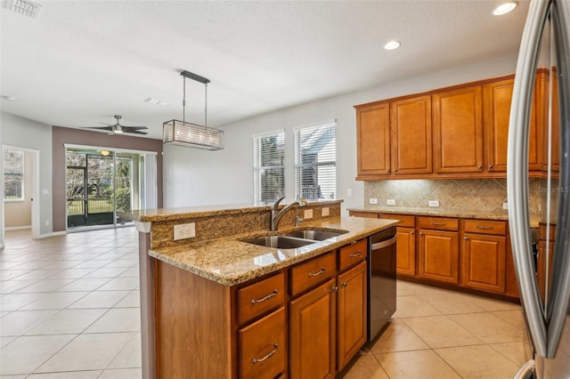 kitchen featuring sink, stainless steel refrigerator, dishwashing machine, an island with sink, and pendant lighting