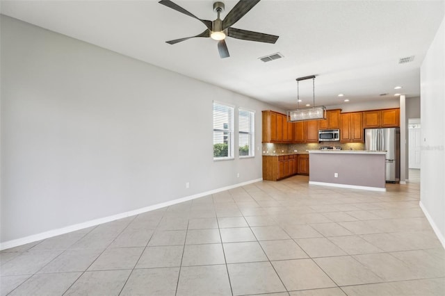 kitchen with light tile patterned flooring, tasteful backsplash, appliances with stainless steel finishes, a kitchen island, and pendant lighting