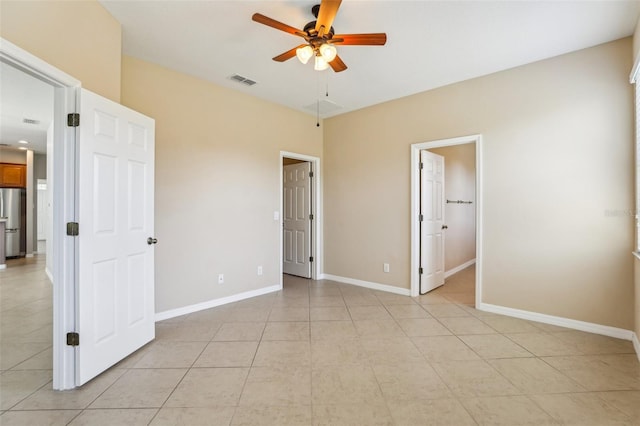 unfurnished bedroom with light tile patterned flooring, ceiling fan, and stainless steel fridge