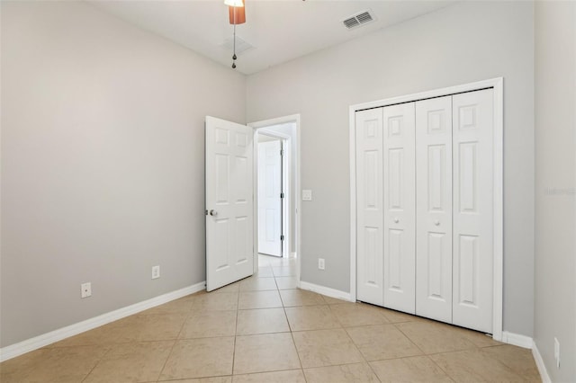 unfurnished bedroom with light tile patterned floors, a closet, and ceiling fan