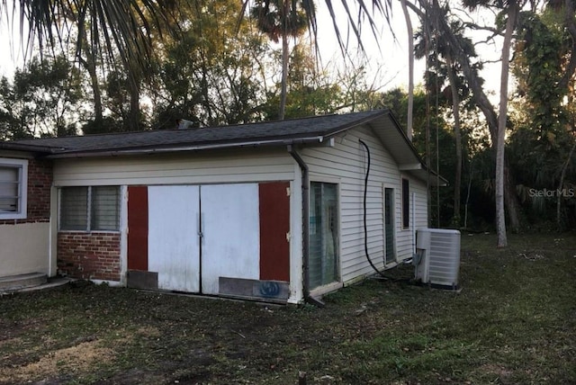 view of outdoor structure featuring a lawn and central air condition unit