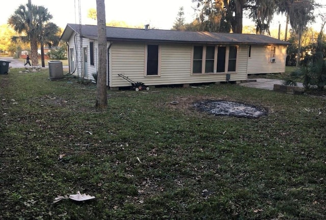 back house at dusk featuring a lawn